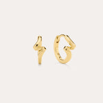 The image shows two small 18k gold plated stud earrings—one a lightning bolt, the other a looping squiggle—styled with Ribbon Twist Huggies in Gold, all set against an off-white background for a chic presentation.