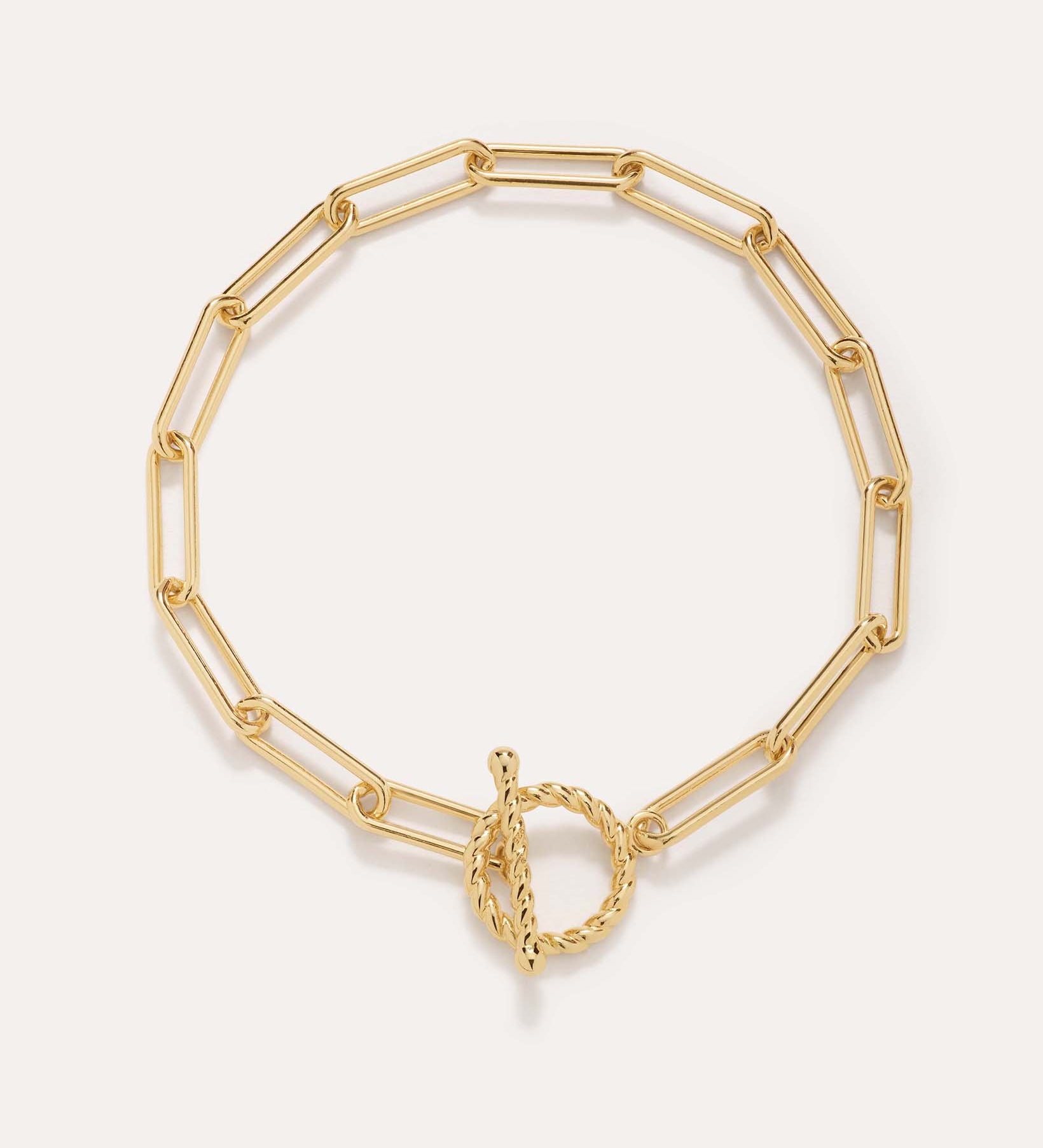 The Paperclip Toggle Bracelet in Gold, crafted in 18k gold plated finish with elongated oval links and a twisted toggle clasp, is shown against a plain light background.