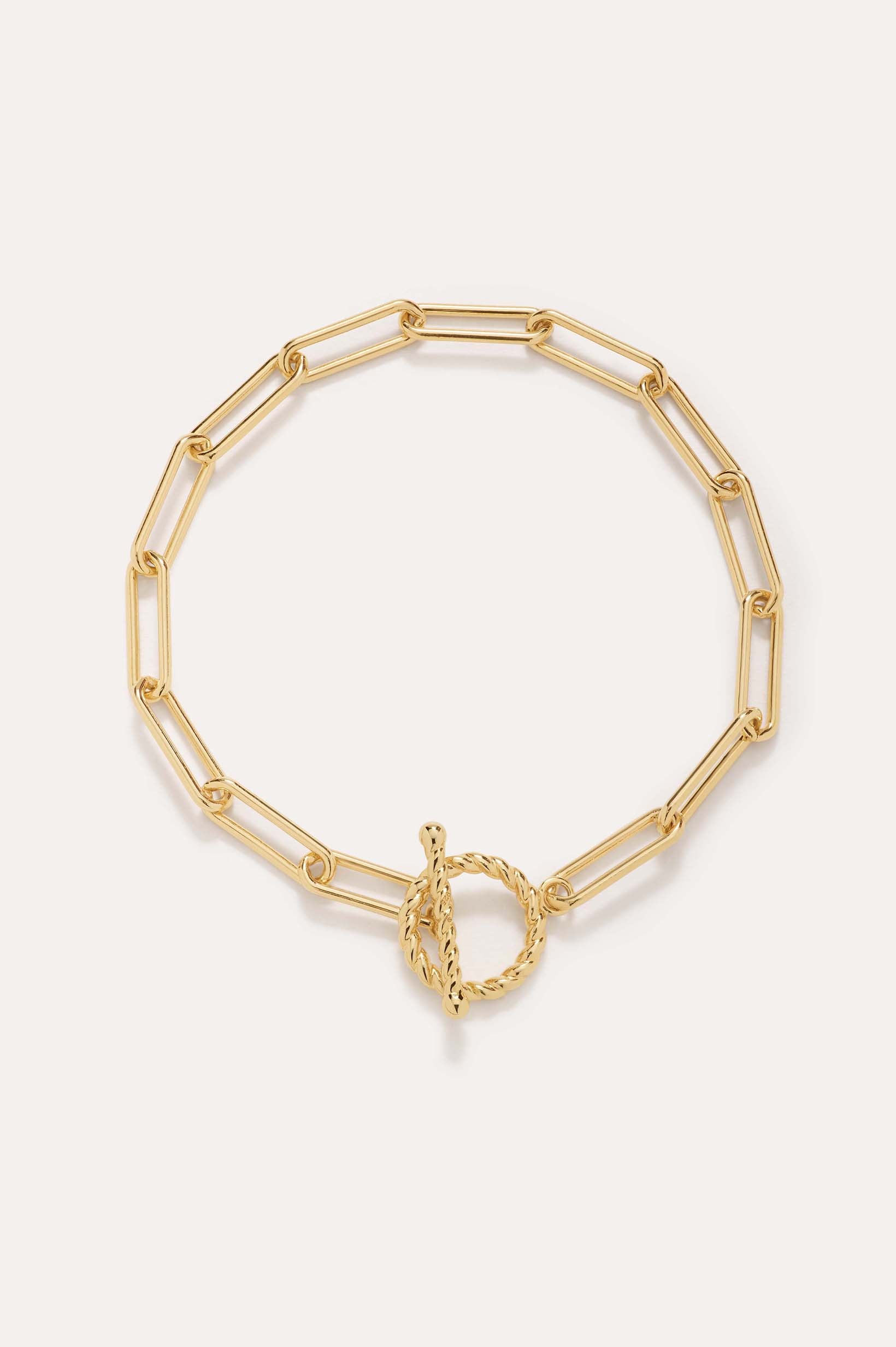 The Paperclip Toggle Bracelet in Gold, crafted in 18k gold plated finish with elongated oval links and a twisted toggle clasp, is shown against a plain light background.