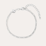 The Figaro And Box Chain Layered Bracelet in Sterling Silver features an adjustable extension, lobster clasp, and a small geometric charm. Shown on a light background, this delicate bracelet is perfect for everyday wear.