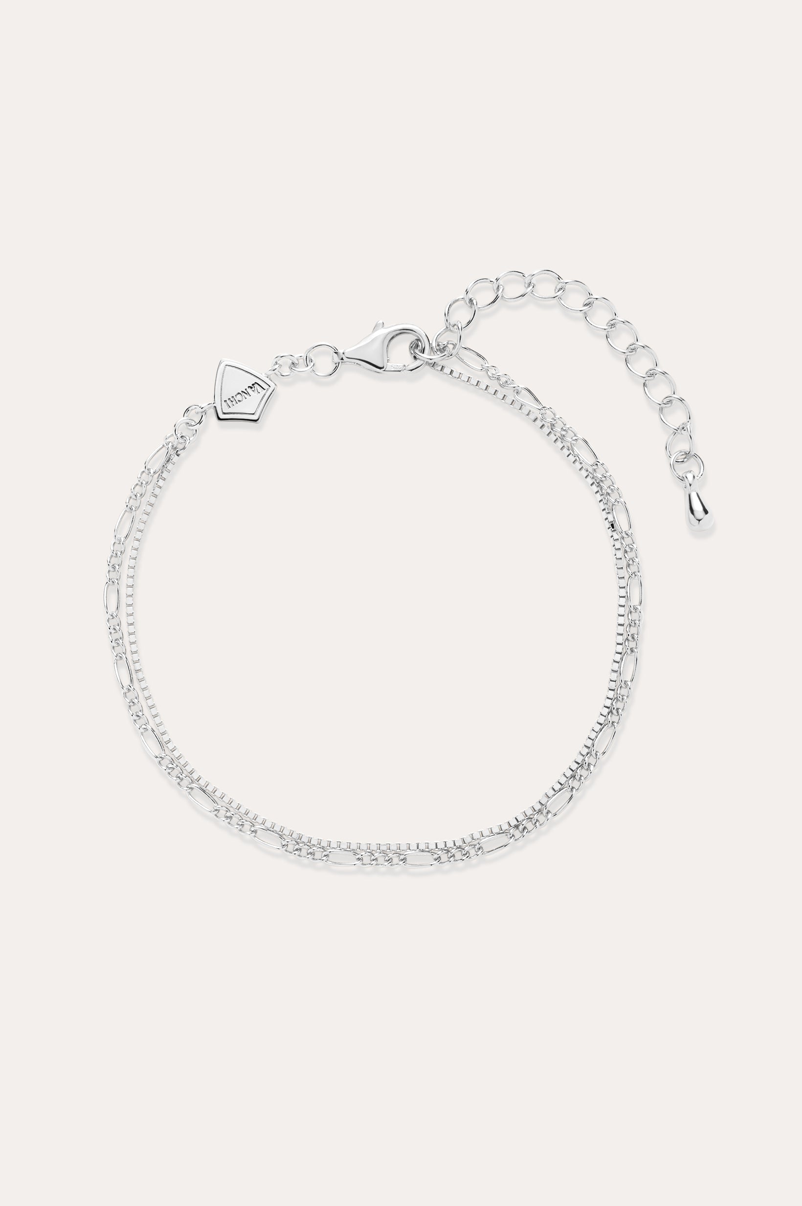 The Figaro And Box Chain Layered Bracelet in Sterling Silver features an adjustable extension, lobster clasp, and a small geometric charm. Shown on a light background, this delicate bracelet is perfect for everyday wear.