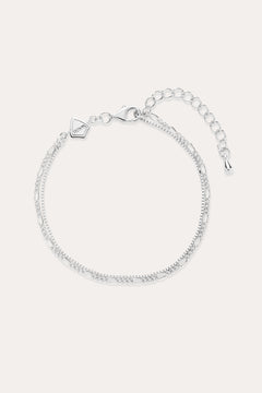 The Figaro And Box Chain Layered Bracelet in Sterling Silver features an adjustable extension, lobster clasp, and a small geometric charm. Shown on a light background, this delicate bracelet is perfect for everyday wear.