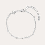 The Pia Crystal Link Bracelet in Sterling Silver features a twist chain with small clear crystals, an adjustable extension, a lobster clasp, and a heart-shaped charm near the clasp.