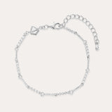 The Pia Crystal Link Bracelet in Sterling Silver features a twist chain with small clear crystals, an adjustable extension, a lobster clasp, and a heart-shaped charm near the clasp.