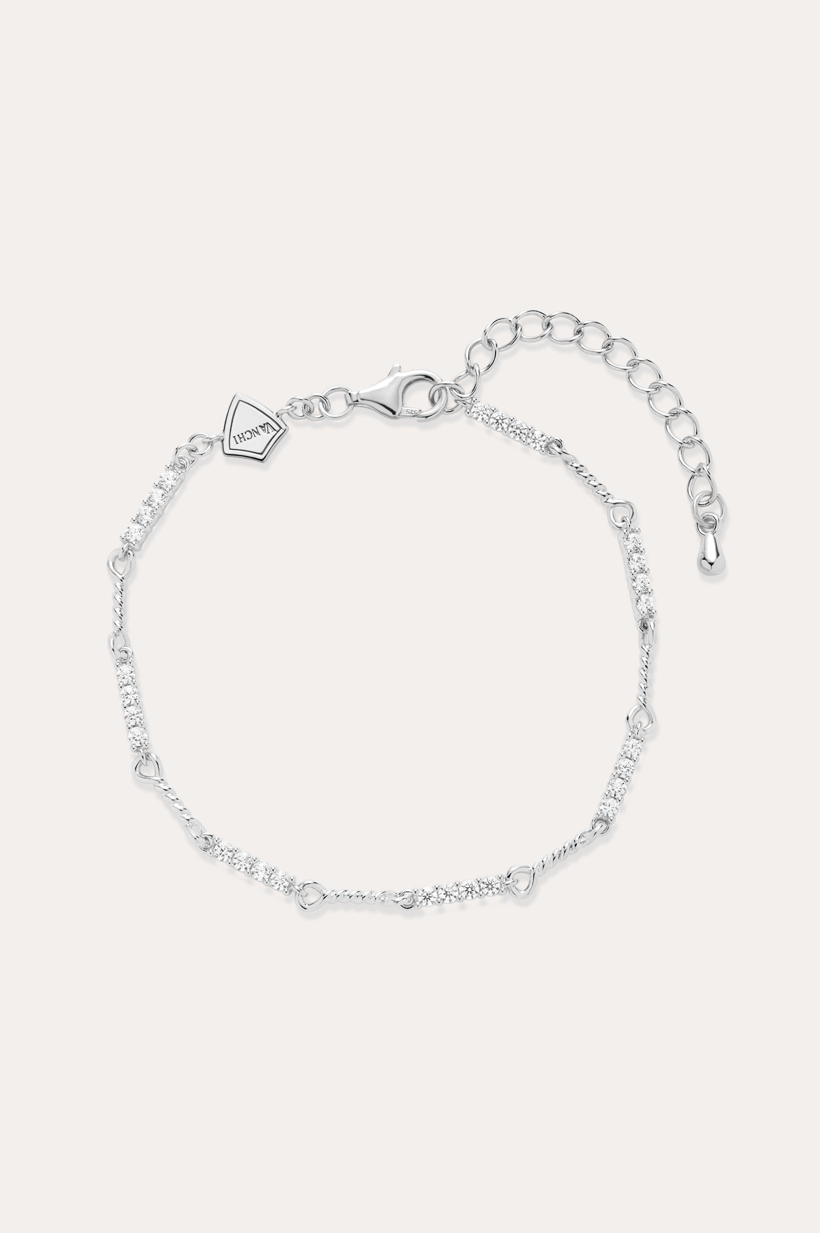 The Pia Crystal Link Bracelet in Sterling Silver features a twist chain with small clear crystals, an adjustable extension, a lobster clasp, and a heart-shaped charm near the clasp.