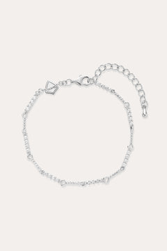 The Pia Crystal Link Bracelet in Sterling Silver features a twist chain with small clear crystals, an adjustable extension, a lobster clasp, and a heart-shaped charm near the clasp.
