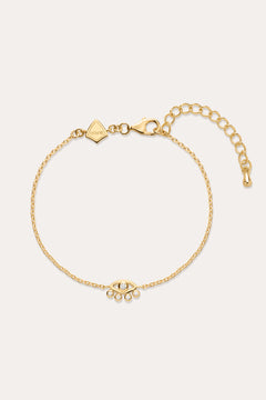 The Defender Evil Eye Bracelet in Gold features an 18k gold-plated finish, an eye-shaped cubic zirconia charm with three dangling crystals, and an adjustable lobster clasp closure.