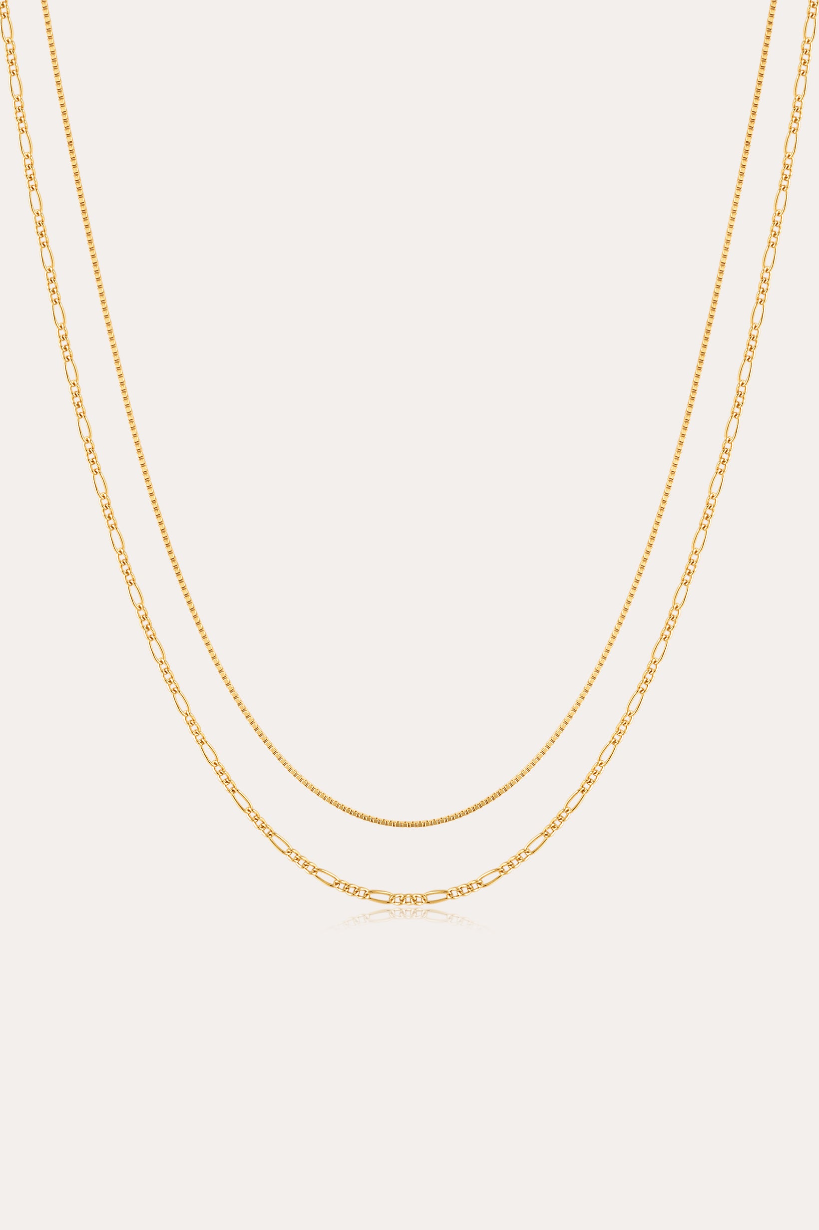 The Figaro And Box Chain Layered Necklace in 18k Gold Plated features a dual design: a sleek box chain above and elongated Figaro links below, beautifully displayed against a white background for an elegant layered look.