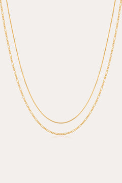 The Figaro And Box Chain Layered Necklace in 18k Gold Plated features a dual design: a sleek box chain above and elongated Figaro links below, beautifully displayed against a white background for an elegant layered look.