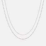 The Figaro And Box Chain Layered Necklace in Sterling Silver features a fine box chain and a longer Figaro link, both displayed against a plain white background for an elegant layered look.