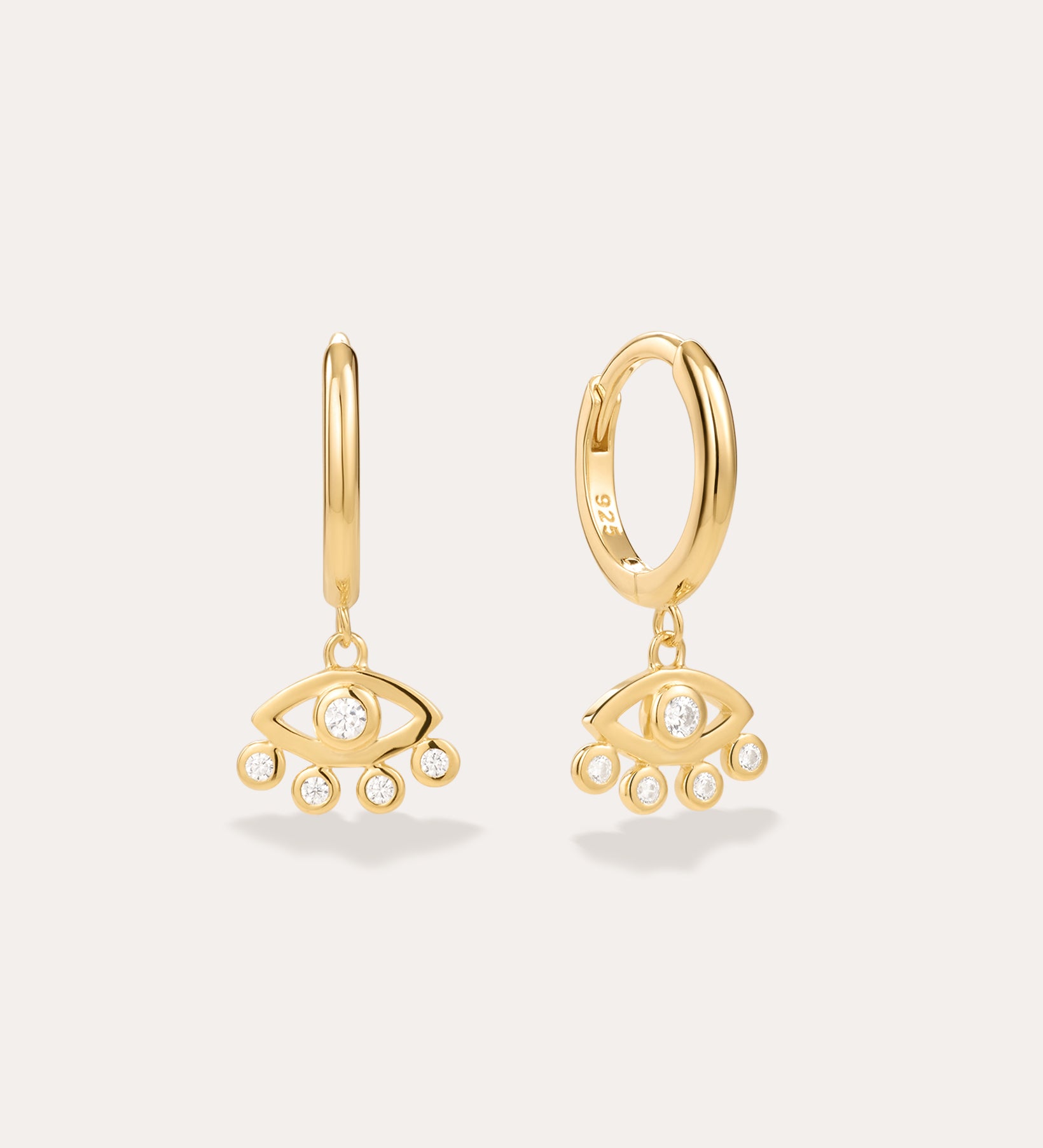 Defender Evil Eye Hoops in 18k Gold Plated, featuring dangling evil eye charms with a central clear stone and four smaller stones on the bottom edge, showcased as unique spiritual jewelry against a plain light background.