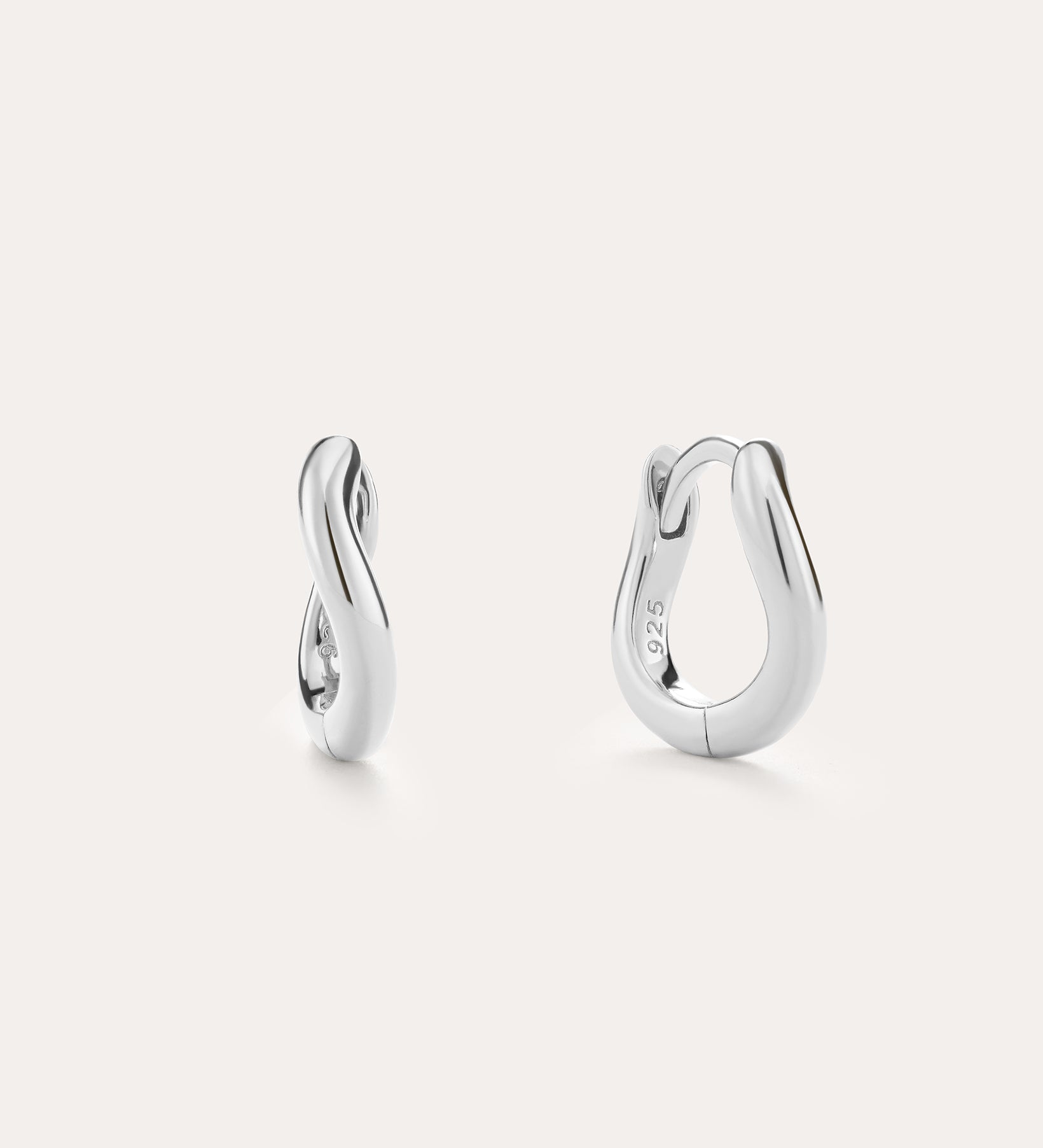 The Nori Mini Twisted Huggies in Sterling Silver feature a sculptural twisted hoop design and are shown against a light, plain background.