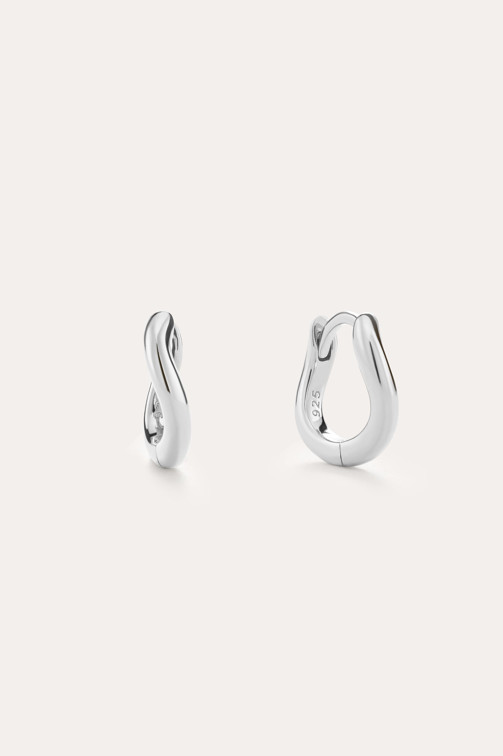 The Nori Mini Twisted Huggies in Sterling Silver feature a sculptural twisted hoop design and are shown against a light, plain background.