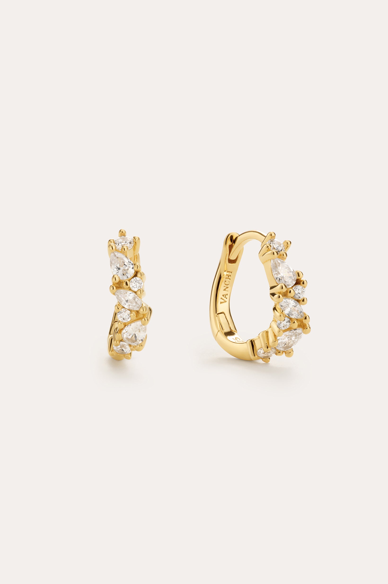 The Nori Twisted Crystal Huggies in Silver, plated in 18k gold, feature a clustered arrangement of marquise and round-cut cubic zirconia—perfect gold earrings to add sparkle to any look. Displayed against a light background.