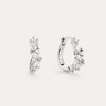 The Nori Twisted Crystal Huggies in Sterling Silver are chic hoops featuring multiple sparkling white crystals, beautifully showcased against a plain, light background.