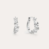 The Nori Twisted Crystal Huggies in Sterling Silver are chic hoops featuring multiple sparkling white crystals, beautifully showcased against a plain, light background.