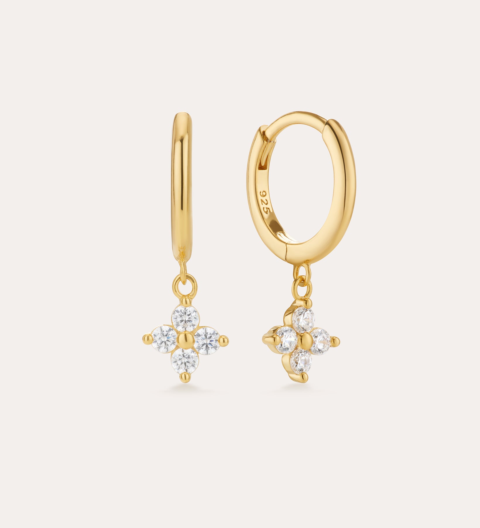 The Flora Crystal Charm Huggies in Gold are 18k gold plated earrings with dangling floral-shaped pendants of five clear gemstones. Shown from both front and side, they display their elegant shine and secure clasp beautifully.
