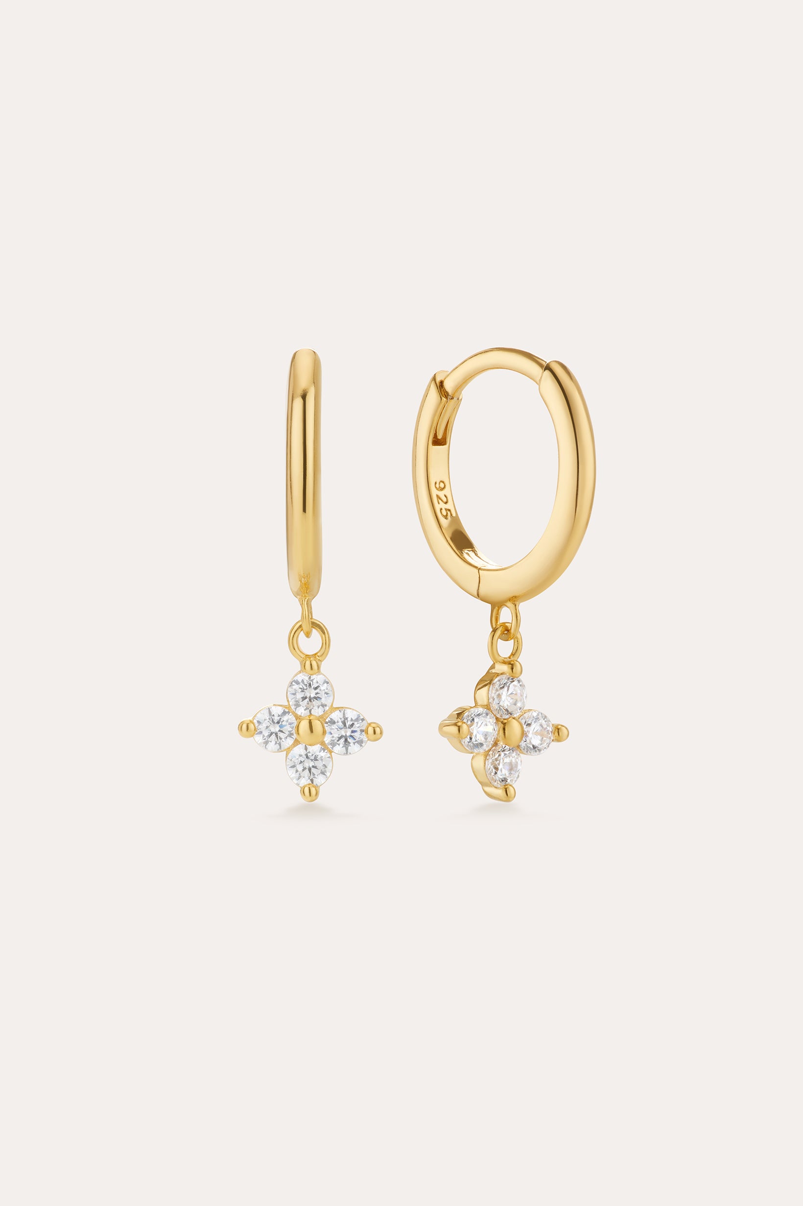 The Flora Crystal Charm Huggies in Gold are 18k gold plated earrings with dangling floral-shaped pendants of five clear gemstones. Shown from both front and side, they display their elegant shine and secure clasp beautifully.