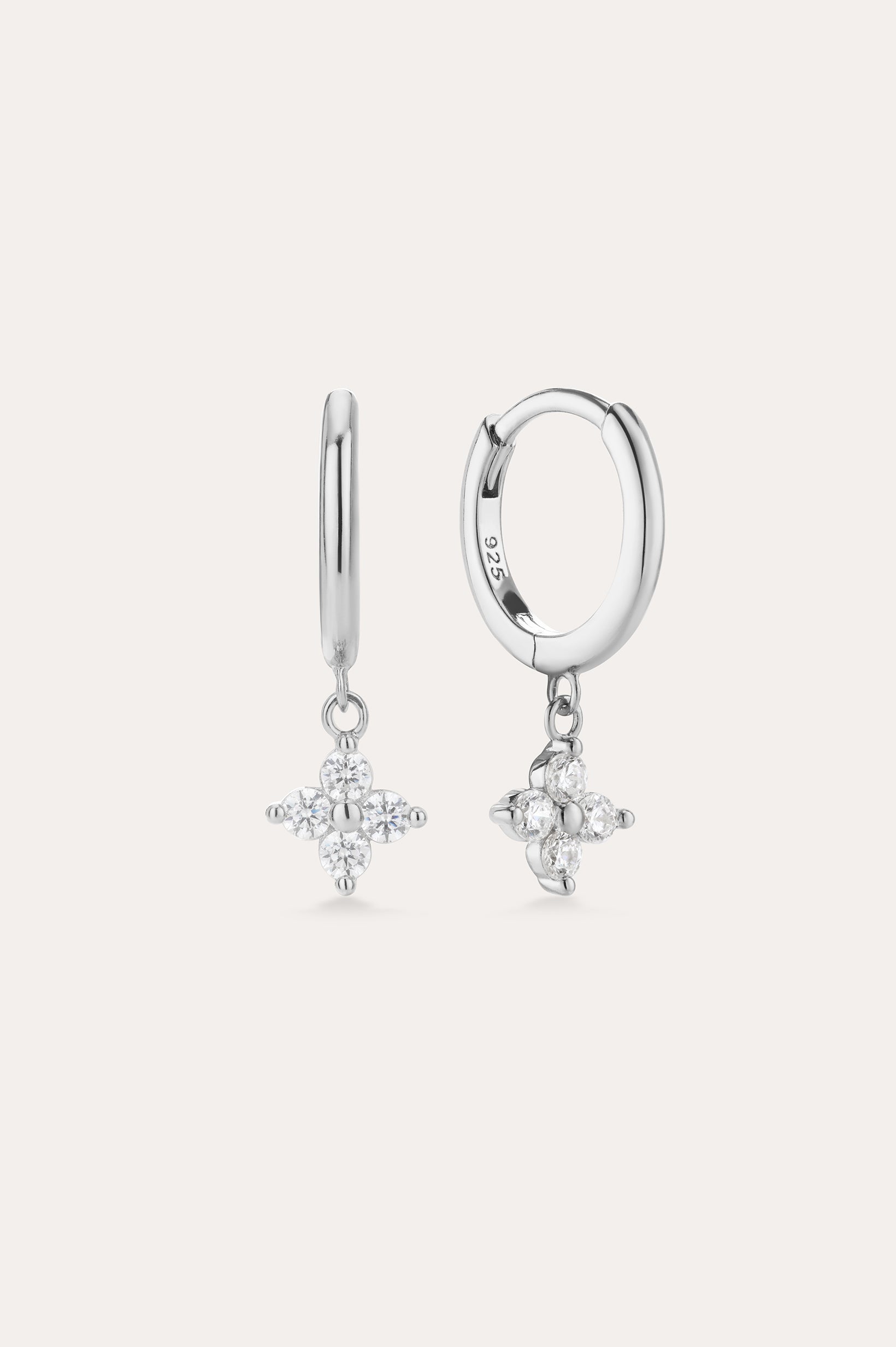 The Flora Crystal Charm Huggies in Sterling Silver feature dangling star-shaped charms with sparkling stones, shown against a plain light background.