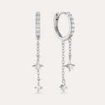 The Star Double Chain Dangle Huggies in Silver feature two sterling silver hoop earrings with star-shaped pendants and cubic zirconia stones along the front for an elegant, sparkling look.