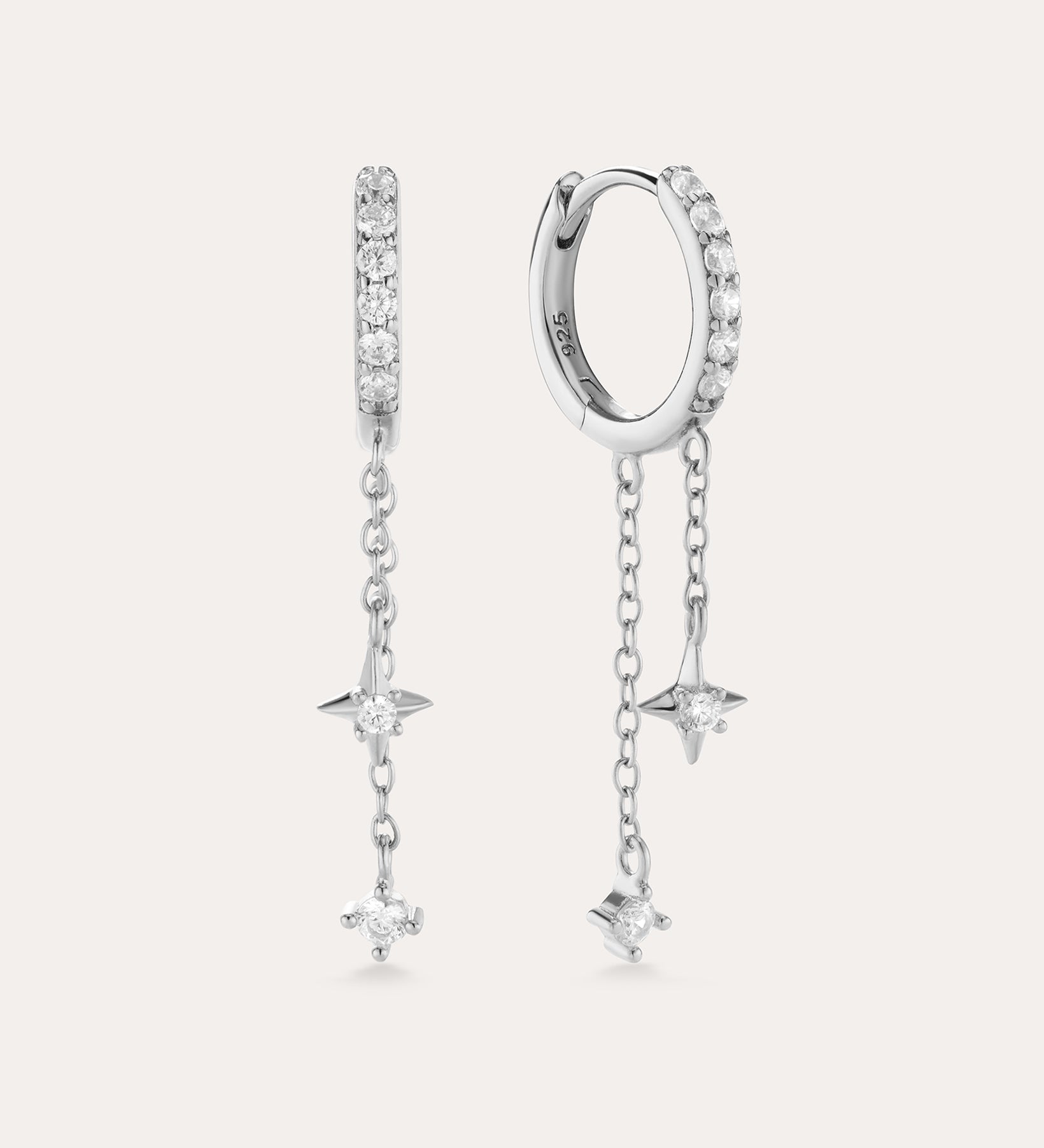 The Star Double Chain Dangle Huggies in Silver feature two sterling silver hoop earrings with star-shaped pendants and cubic zirconia stones along the front for an elegant, sparkling look.