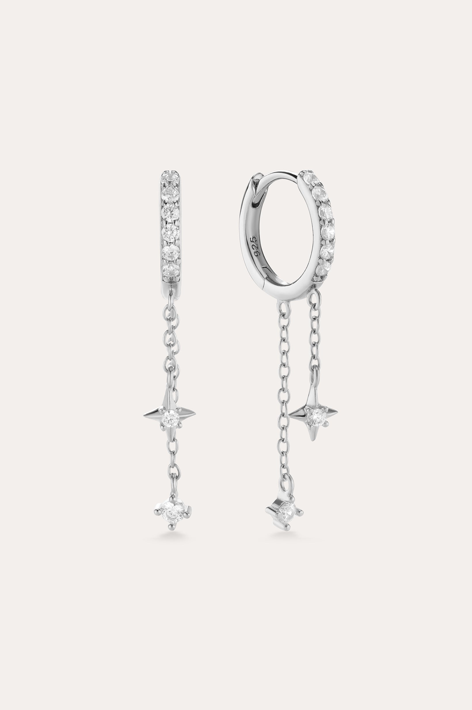 The Star Double Chain Dangle Huggies in Silver feature two sterling silver hoop earrings with star-shaped pendants and cubic zirconia stones along the front for an elegant, sparkling look.