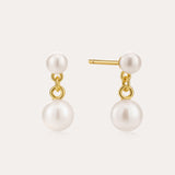 The Double Freshwater Pearl Drop Stud Earrings in Silver feature small and large round white freshwater pearls, with the larger pearls dangling below 18k Gold Plated studs against a light backdrop.