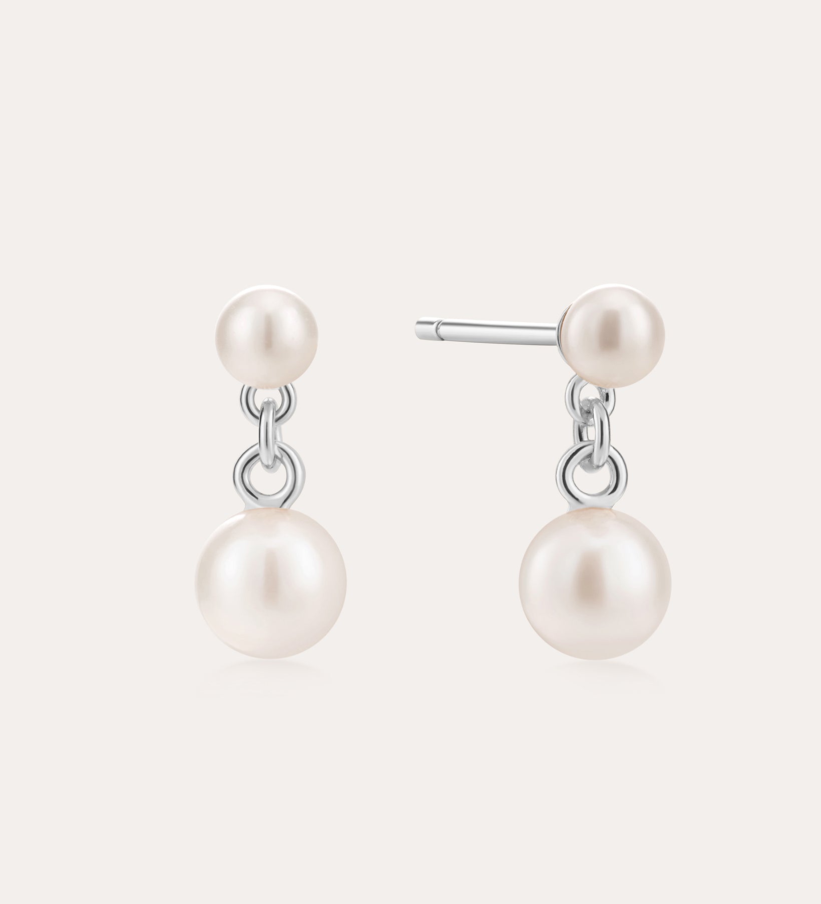 The Double Freshwater Pearl Drop Stud Earrings in Silver feature two lustrous freshwater pearls on each sterling silver stud, designed with a minimalist touch and a radiant finish.