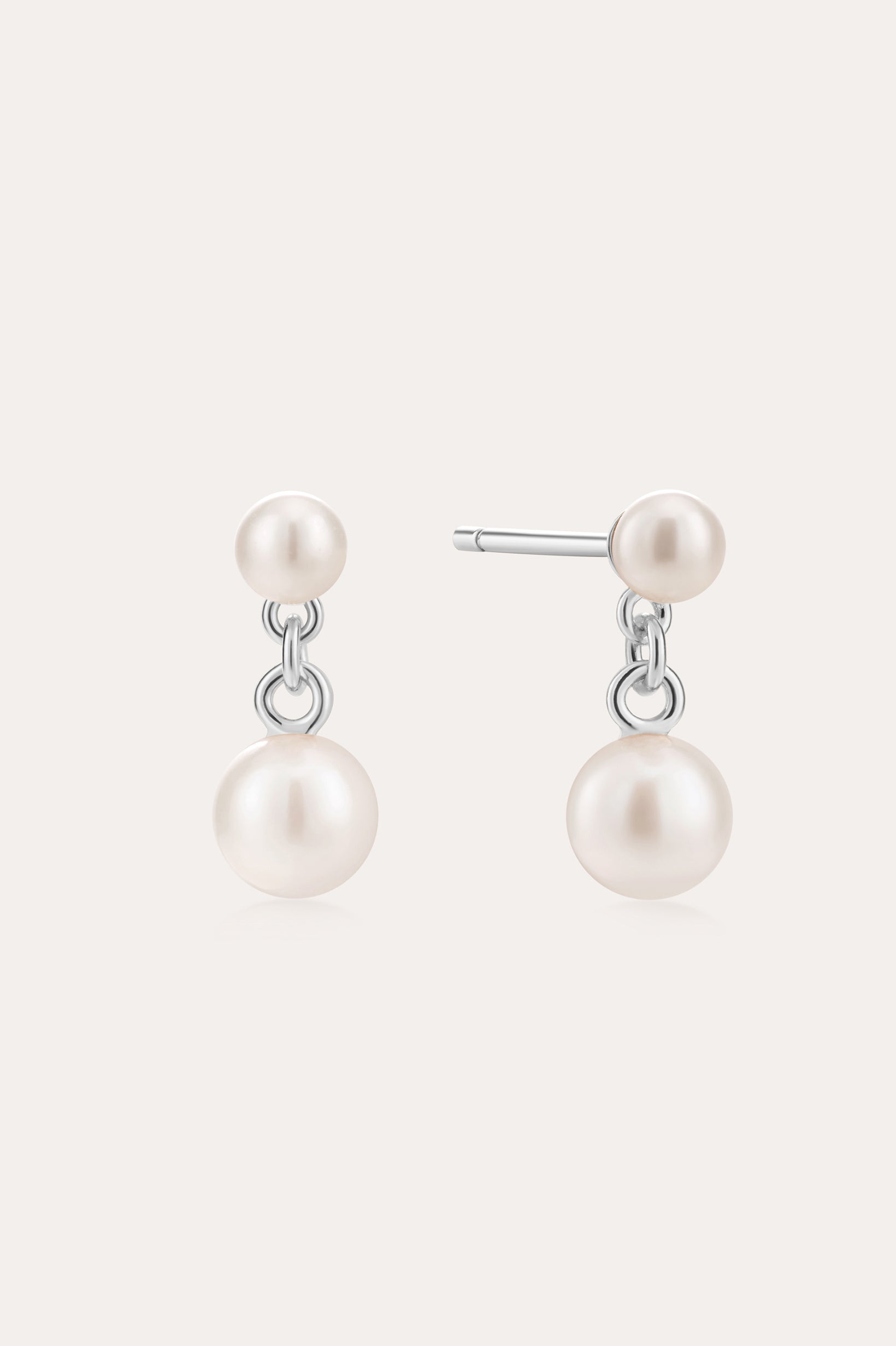 The Double Freshwater Pearl Drop Stud Earrings in Silver feature two lustrous freshwater pearls on each sterling silver stud, designed with a minimalist touch and a radiant finish.