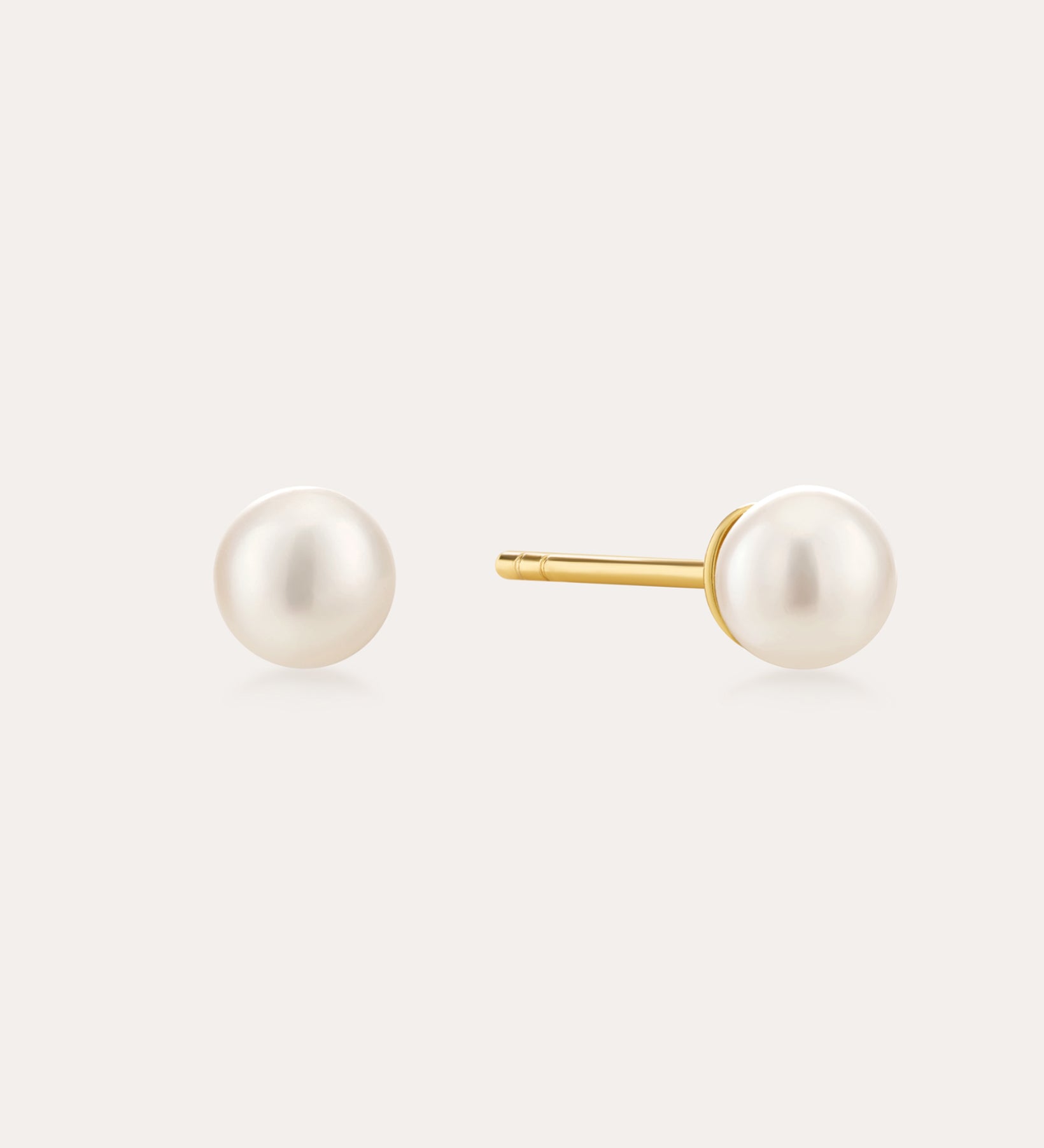 The Freshwater Pearl Studs in Gold feature round white pearls on 18k gold plated posts, shown against a plain light background.