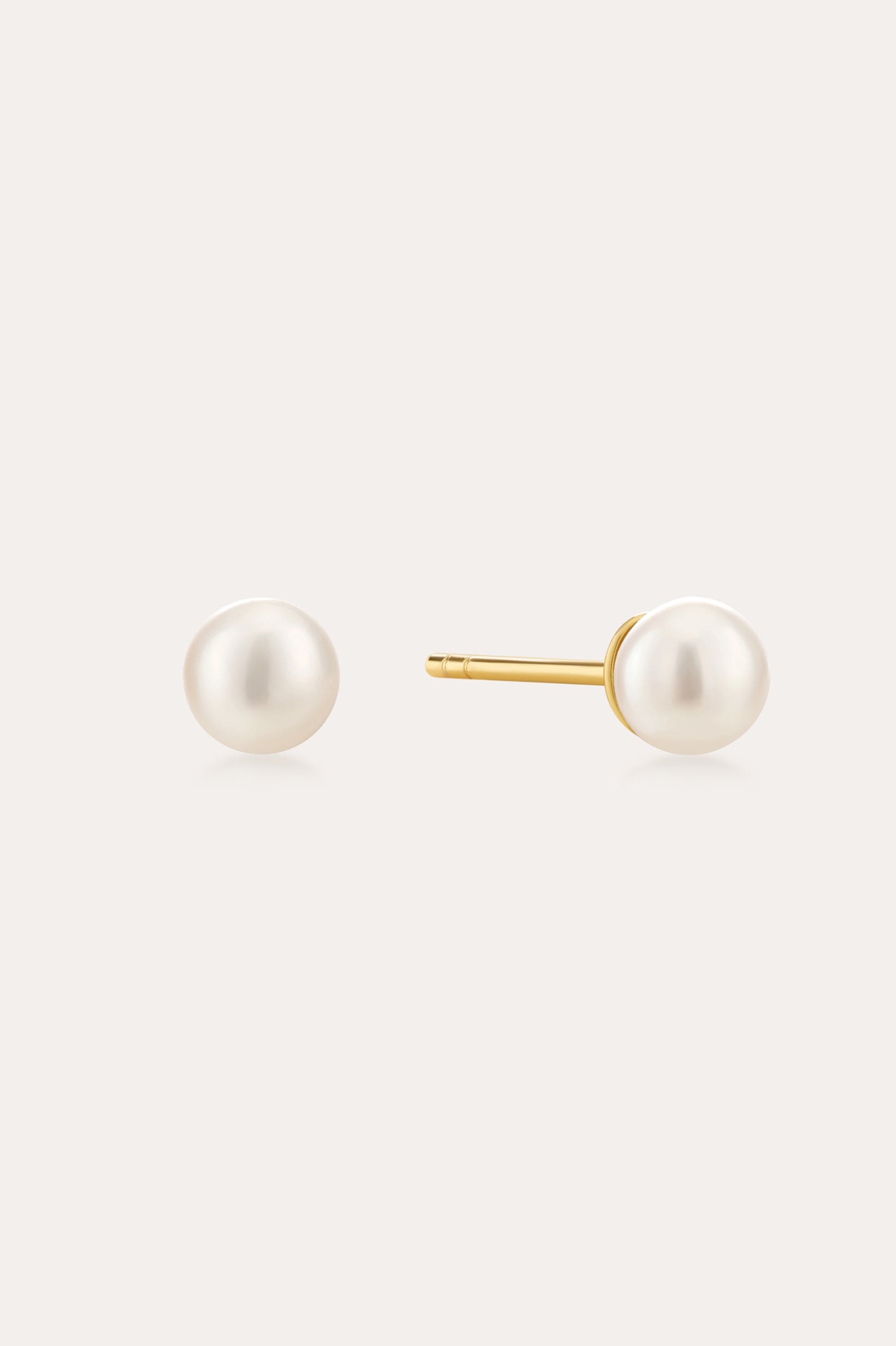 The Freshwater Pearl Studs in Gold feature round white pearls on 18k gold plated posts, shown against a plain light background.