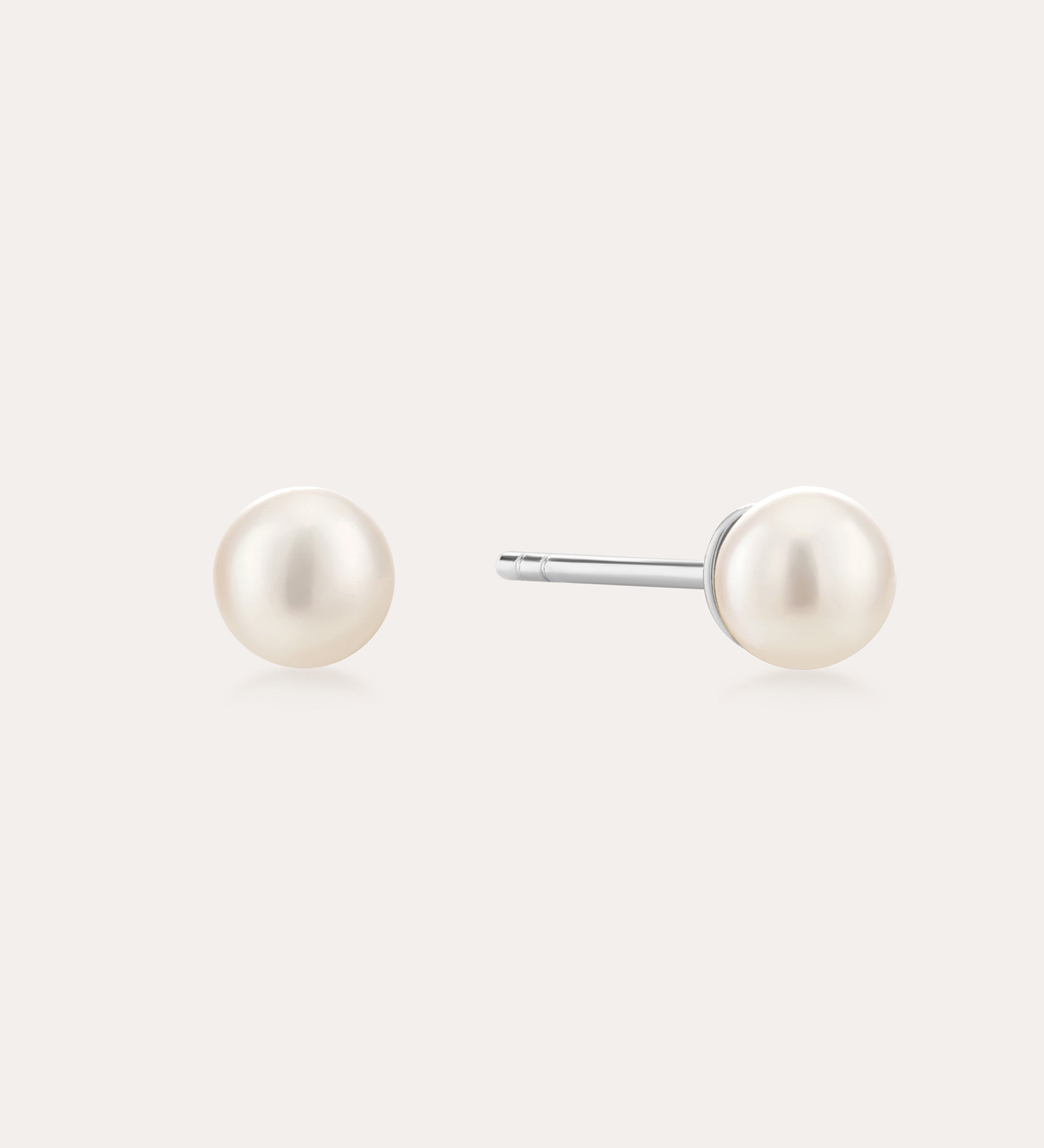 A pair of Freshwater Pearl Studs in Gold featuring round white pearls on sterling silver posts, shown against a plain light background.