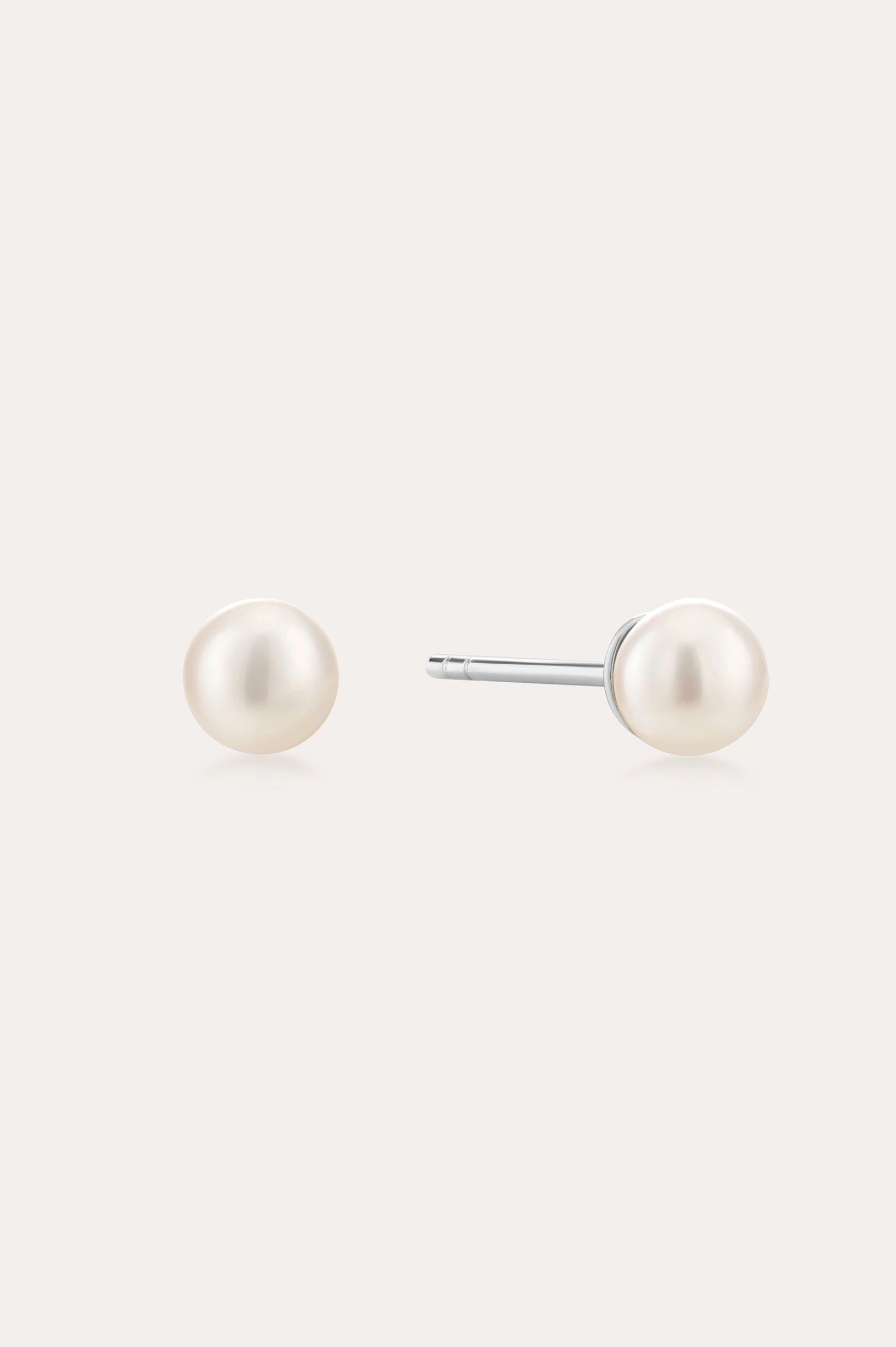 A pair of Freshwater Pearl Studs in Gold featuring round white pearls on sterling silver posts, shown against a plain light background.