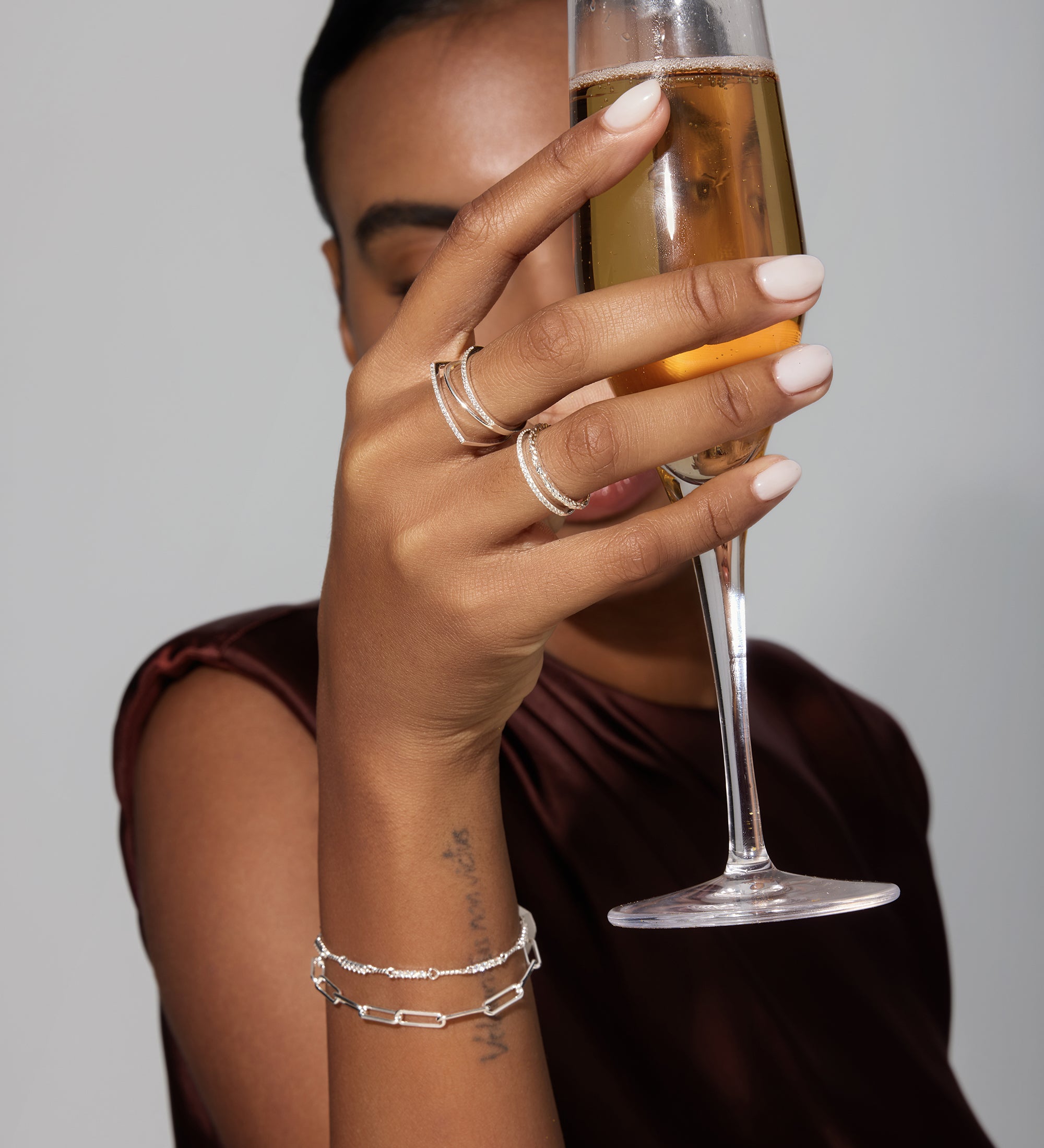 Person holding a glass of champagne with a neutral background