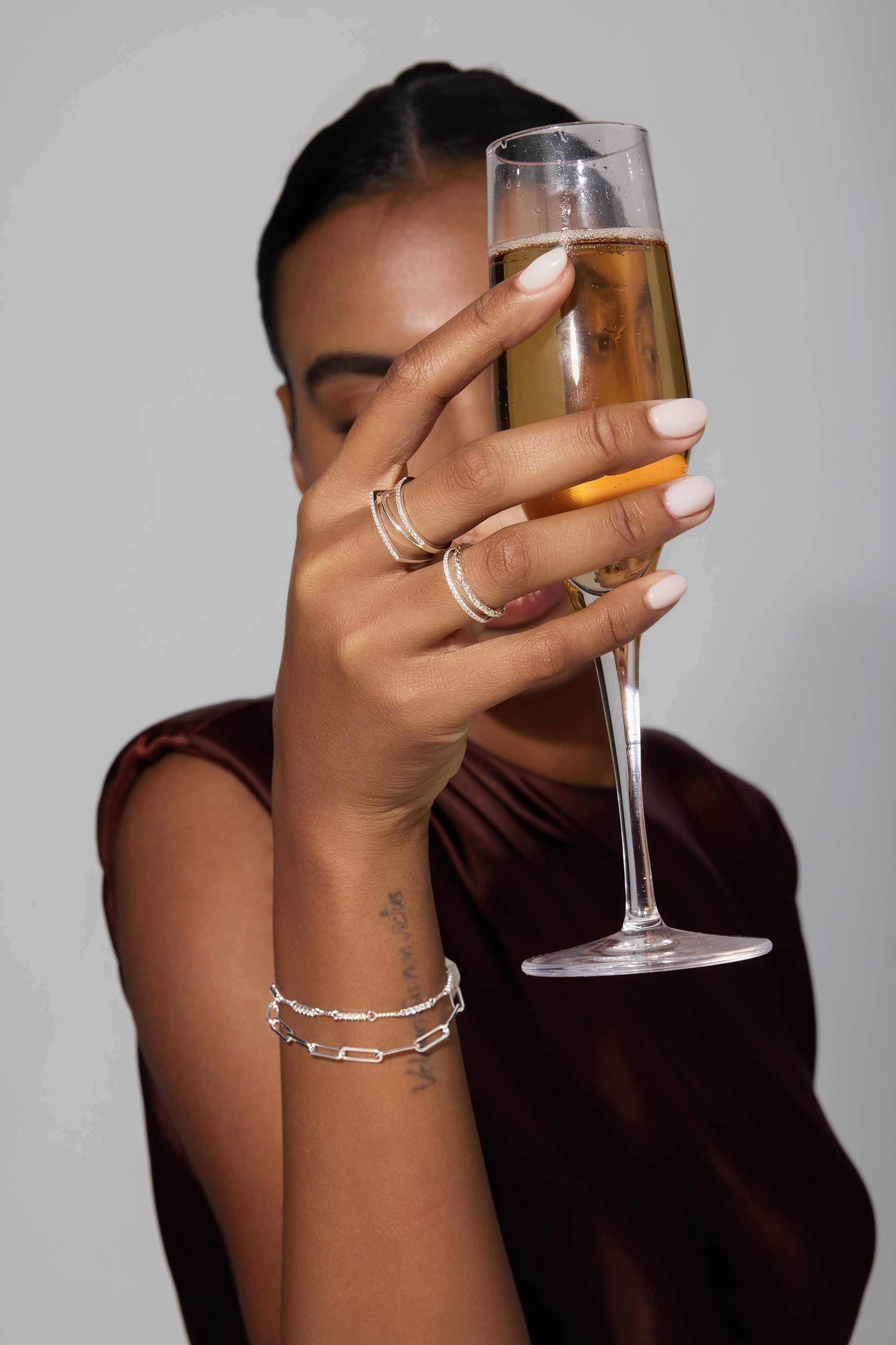 Person holding a glass of champagne with a neutral background