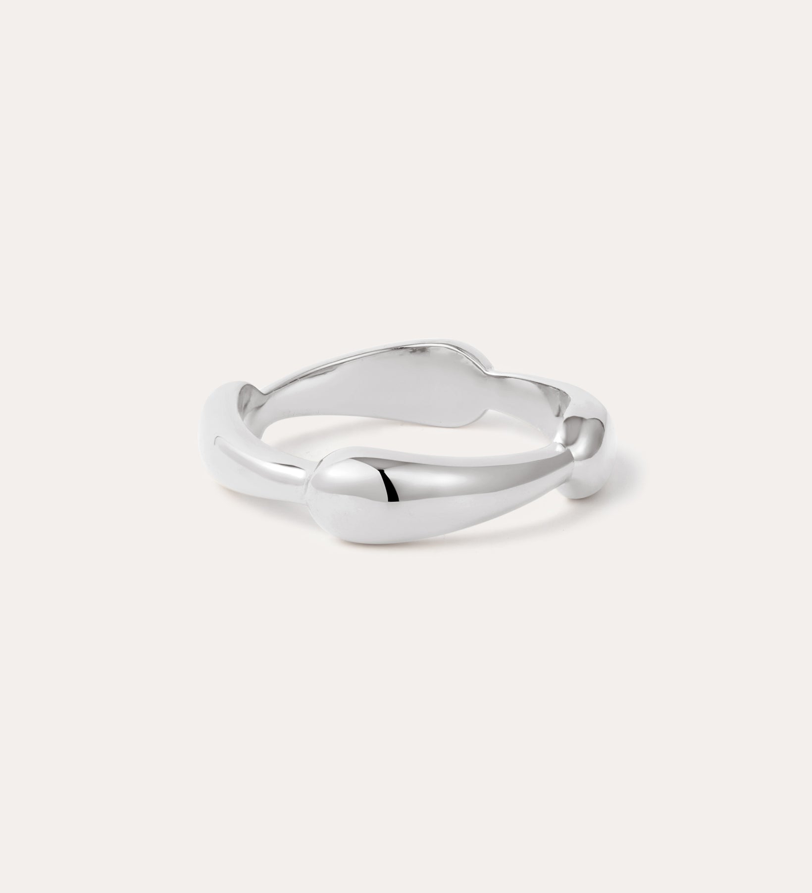 The Colette Link Droop Ring in Silver features a minimalist design with a smooth, slightly irregular band and rounded ends, shown against a light background.