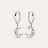Crescent Moon Crystal Charm Huggies in Silver feature dangling crescent moon charms with sparkling cubic zirconia, shown on a light background.