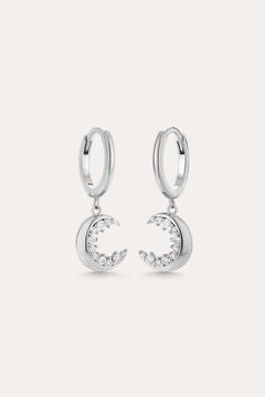 Crescent Moon Crystal Charm Huggies in Silver feature dangling crescent moon charms with sparkling cubic zirconia, shown on a light background.