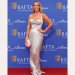 SPOTTED ON: Emily Norris wears Eden Trio Pearl Drop Earrings in Gold with a silver gown and pink clutch at the BAFTA Television Awards. She poses on the red carpet, with BAFTA and sponsor logos in the background.