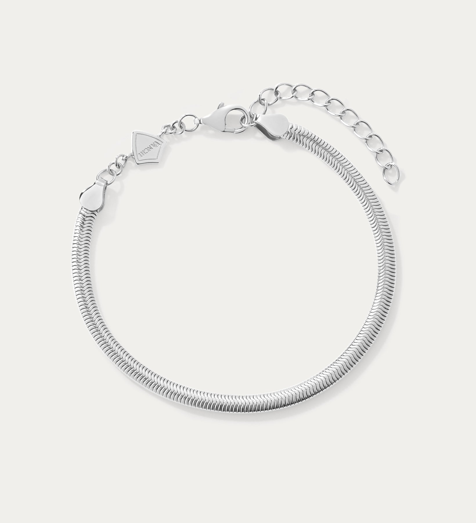 The Estelle Herringbone Chain Bracelet in Silver features a 3mm sleek chain, an adjustable extension, and a small charm by the clasp, shown against a plain white background.