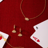 Silver Defender Evil Eye Necklace arranged with matching gold jewelry—bracelet, earrings, and charms—on a red textured surface, surrounded by playing cards like the ace of hearts and king.