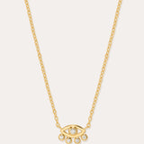 The Defender Evil Eye Necklace in Gold features an 18k gold-plated eye-shaped pendant with a central cubic zirconia and four dangling crystals, shown on a plain white background.