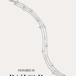 The Simone Triple Chain Layered Bracelet in Silver, featuring three delicate sterling silver chains and round accents, is displayed on a white background with the text: Featured in Harper’s Bazaar.