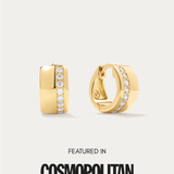 The Juni Pavé Chunky Huggie Earrings in Gold feature a vertical row of small white gemstones and are displayed on a light background above the text "Featured in Cosmopolitan.