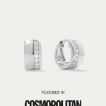 The Juni Pavé Chunky Huggie Earrings in Silver, hypoallergenic and perfect for daily wear, feature a vertical row of sparkling cubic zirconia and are displayed on a white background above the words "Featured in Cosmopolitan.