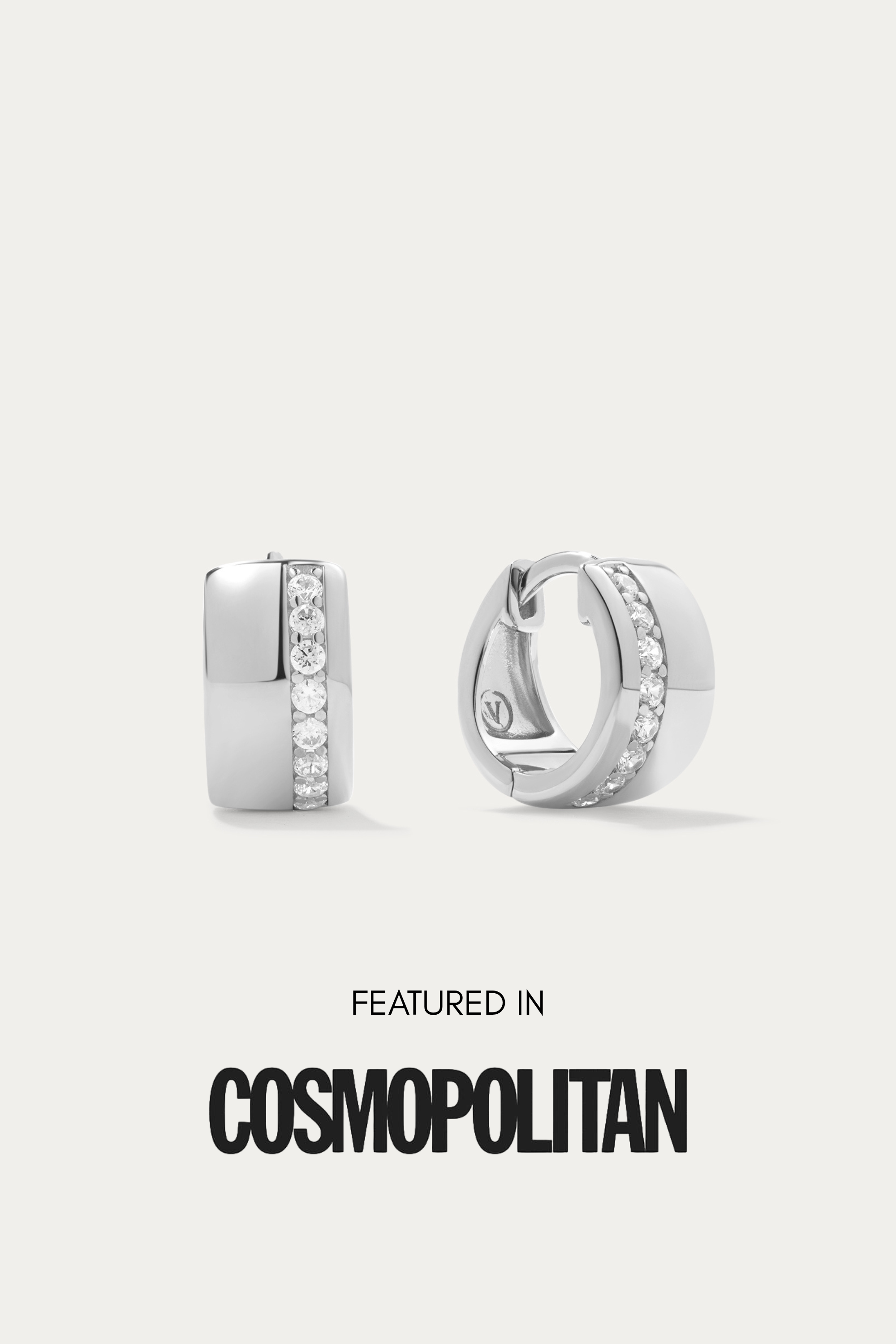 The Juni Pavé Chunky Huggie Earrings in Silver, hypoallergenic and perfect for daily wear, feature a vertical row of sparkling cubic zirconia and are displayed on a white background above the words "Featured in Cosmopolitan.
