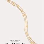 The Simone Triple Chain Layered Bracelet in Gold, featuring delicate 18k gold plating and small round accents, is shown against a plain light background. Text at the bottom reads: FEATURED IN Harper’s BAZAAR.