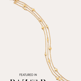 The Simone Triple Chain Layered Bracelet in Gold, featuring delicate 18k gold plating and small round accents, is shown against a plain light background. Text at the bottom reads: FEATURED IN Harper’s BAZAAR.