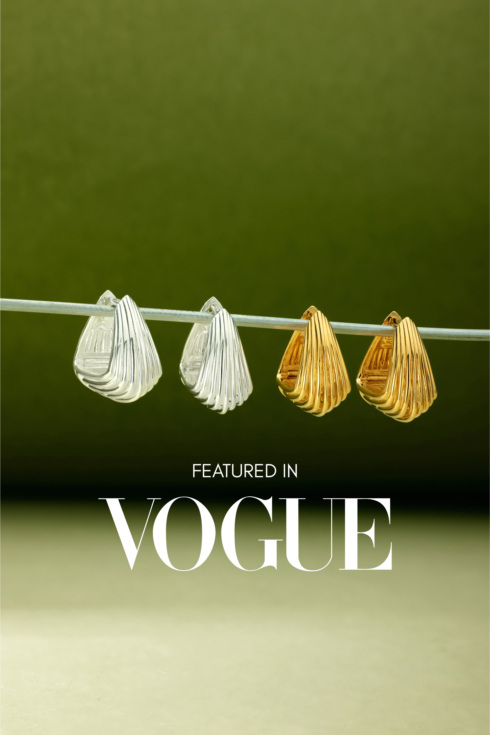 Two pairs of sculptural hoop earrings, including the Juno Ridged Chunky Hoops in Gold, hang on a clear rod against a green background. The text Featured in VOGUE appears at the bottom of the image.