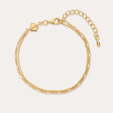 The Figaro And Box Chain Layered Bracelet in 18k Gold Plated features two intertwined strands in a mini Figaro box chain design with a lobster clasp, adjustable extender, and geometric tag, shown on a plain off-white background.